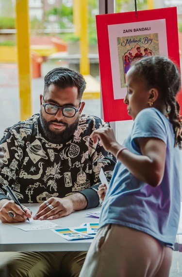 Author Zain Bandali signs an autograph for a young Black reader.